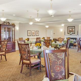 A cozy dining room with elegant chairs and tables, decorative lighting, and carpeted flooring.