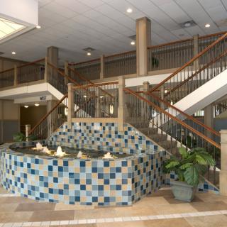 A spacious lobby featuring a decorative tiled fountain and a dual staircase.