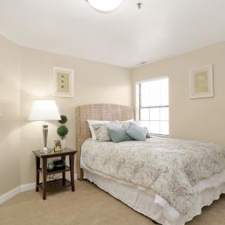 A cozy bedroom with a bed, side table, lamp, and wall decor.