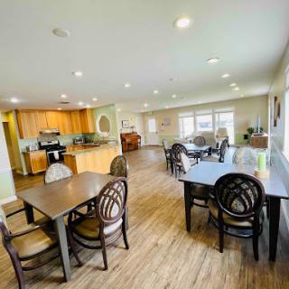 A spacious and modern dining area with a view of the kitchen, featuring wooden floors and ample natural light.