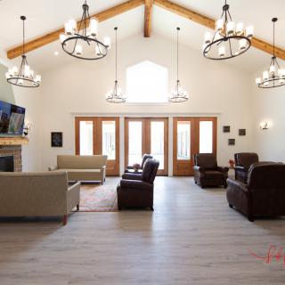 Spacious living room with rustic chandeliers and wood beam accents.