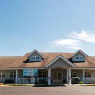 A single-story house with a symmetrical design and a large front porch under a clear blue sky.