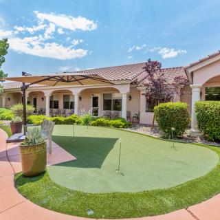 A backyard view of a house featuring a patio and a putting green.