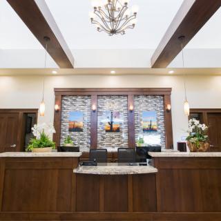 A well-lit hotel reception area featuring a wooden desk, decorative lighting, and elegant interior design.