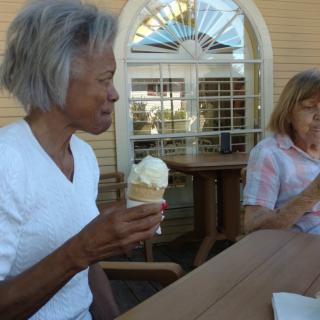 Two people enjoying ice cream and conversation outdoors on a sunny day.