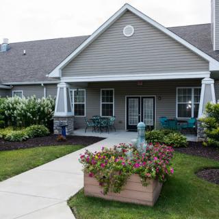 A quaint house with a well-maintained garden and a flower-filled planter by the entrance.