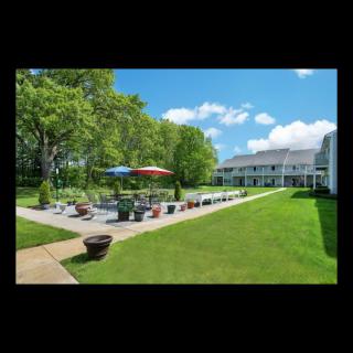 A sunny day at a patio area with colorful umbrellas, surrounded by green lawns and trees.