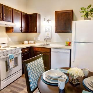 A cozy kitchen with wood cabinets, a dining table set, and standard kitchen appliances.