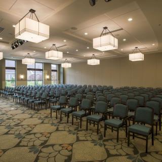 An empty conference room setup with rows of chairs and overhead lighting.