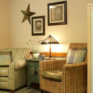 A cozy living room corner with armchairs, decorative wall art, and a warm lamp.