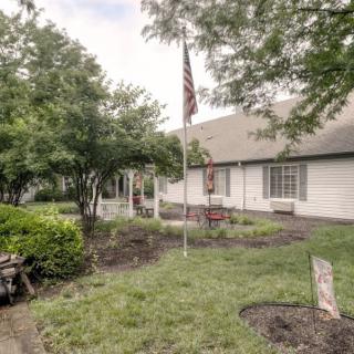 A suburban home with a well-maintained garden, featuring a flagpole and surrounded by trees.