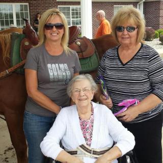 Three women enjoying a day outdoors, with one sitting in a wheelchair.