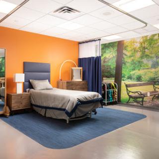 A well-designed hospital room featuring a bed, modern furniture, and a nature-themed mural.