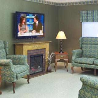 A cozy living room with a television above the fireplace and comfortable seating.