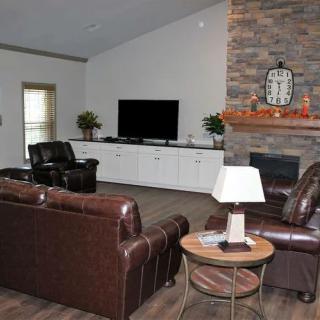 A cozy living room with leather sofas, a fireplace, and a flat-screen TV.