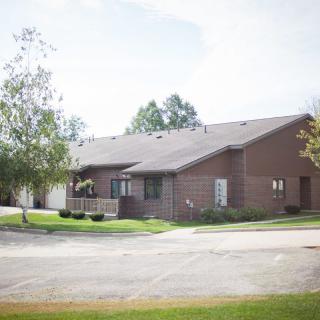 A suburban brick house with a well-maintained lawn and surrounding trees.