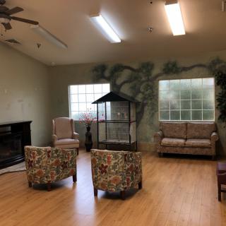 A cozy living room with seating, large windows, and a fireplace.