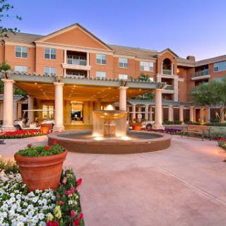 A beautiful hotel entrance featuring a serene fountain and vibrant landscaping.