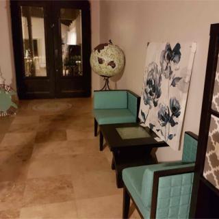 A stylish hallway featuring turquoise chairs, a globe, and floral artwork.