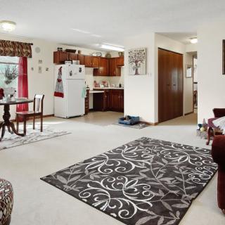 An open living space with a view of the kitchen area, featuring cozy furniture and decorative elements.