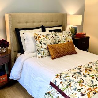 A cozy, well-decorated bedroom featuring a bed with floral patterned bedding and accent pillows.