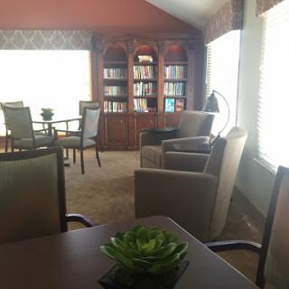 A cozy reading area featuring comfortable chairs, a bookcase, and plenty of natural light.
