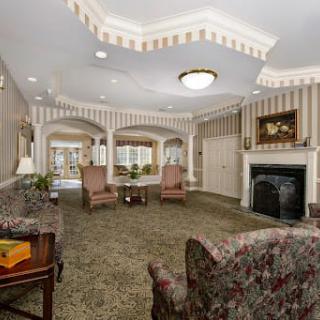 A traditionally decorated living room featuring armchairs, a fireplace, and a chandelier.