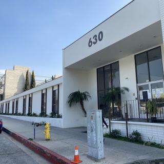 A modern building with a clean design located at 630, featuring large windows and palm trees.