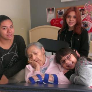 A family gathered around an elderly woman, showcasing moments of togetherness and care.