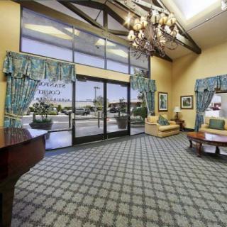 A spacious hotel lobby with elegant furnishings, large windows, and a chandelier.