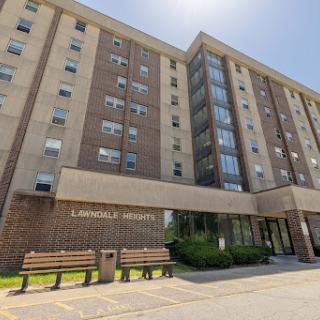 A modern multistory residential building with large windows under a clear blue sky.