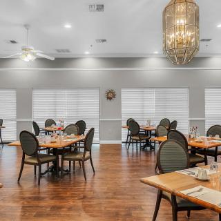 A spacious dining room featuring elegant table settings and a grand chandelier.