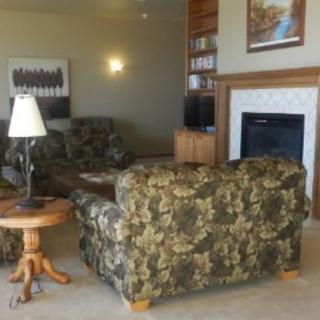 A cozy living room featuring camouflage-patterned sofas, a wooden side table with a lamp, and a fireplace.