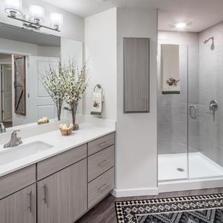 A modern bathroom with a glass shower, large mirror, and elegant decor.