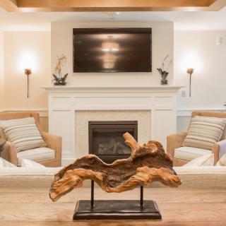 A cozy living room with a modern fireplace and a striking wood sculpture centerpiece.