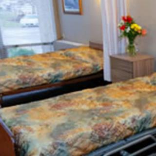 A cozy bedroom with twin beds and a vase of flowers on a nightstand.