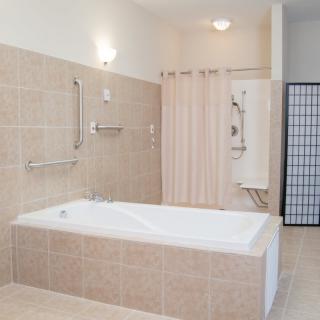 A modern bathroom with a bathtub, shower, and tiled walls.