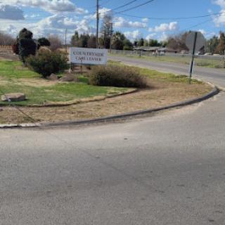 A view of a curved road with a sign and landscaped area.