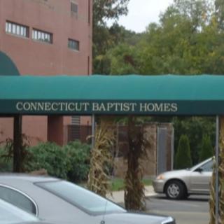 Entrance to Connecticut Baptist Homes with an awning and parked cars.