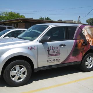 A branded vehicle with advertisement graphics parked in a parking lot.