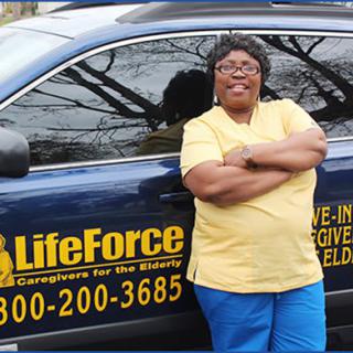 A caregiver stands confidently beside a LifeForce vehicle, showcasing her role in providing care services.