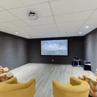 A modern home theater setup featuring a large projector screen and comfortable seating.