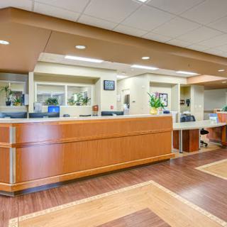 A modern reception area in a hospital featuring a wooden front desk and a well-lit environment.