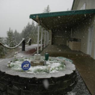 A snowy landscape around a house with a deck.