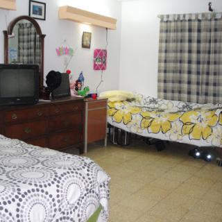 A cozy bedroom featuring two beds with floral bedding, a dresser, and a television.