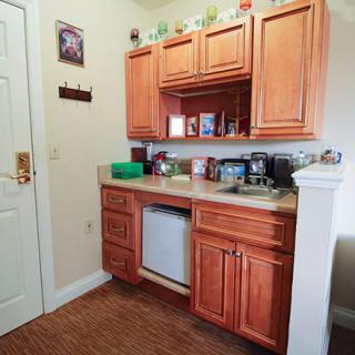 A compact kitchenette featuring wooden cabinets and a small sink, adorned with various decor items.