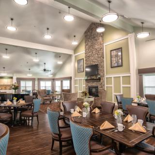 A cozy dining area with elegantly set tables and comfortable seating, featuring warm decor and ambient lighting.