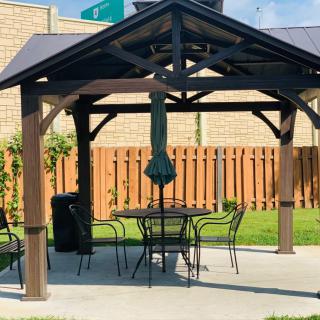 A cozy outdoor gazebo with a table and chairs set under an umbrella, surrounded by a wooden fence.