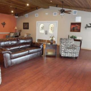 A cozy living room with leather sofas, patterned chairs, and a wooden floor.
