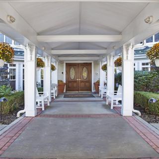 A welcoming entrance with white columns and hanging plants leading to a double door.